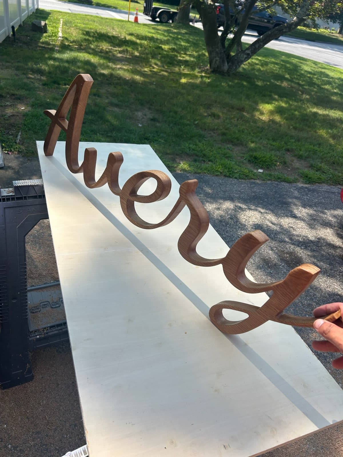 Custom scroll-cut oak name sign in flowing cursive script