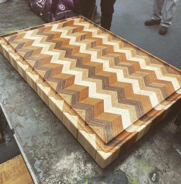 End grain cutting board with chevron pattern made from multiple wood species by Coastal Custom Woodworks